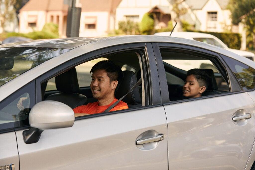 Driver and passenger in a silver sedan parked in a suburban neighborhood
