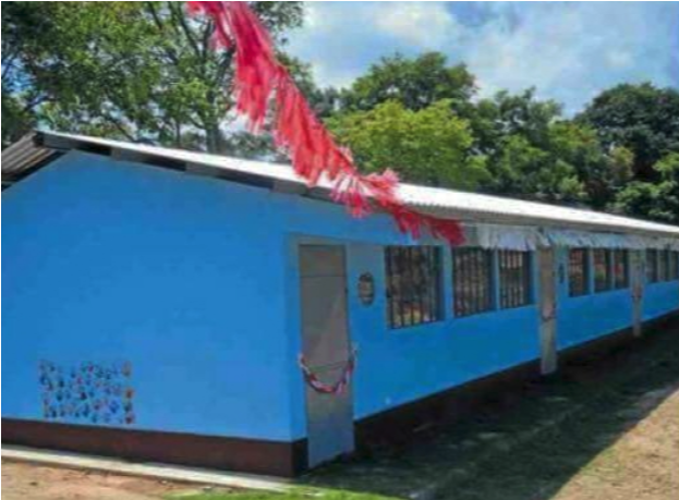 Long single-story bright blue school building decorated with red streamers on the roof and small decorative elements on the wall