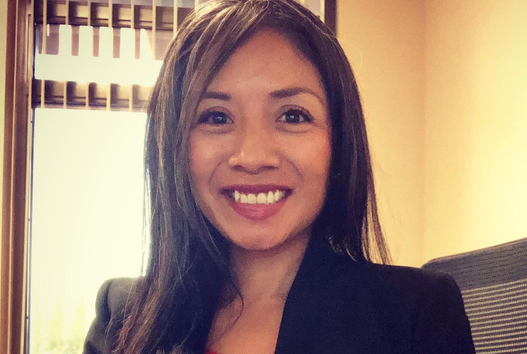 Professional woman wearing black blazer smiling warmly at camera in office setting