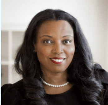 Professional portrait of a woman wearing a black top and pearl necklace, with long dark hair and a warm smile against a light background