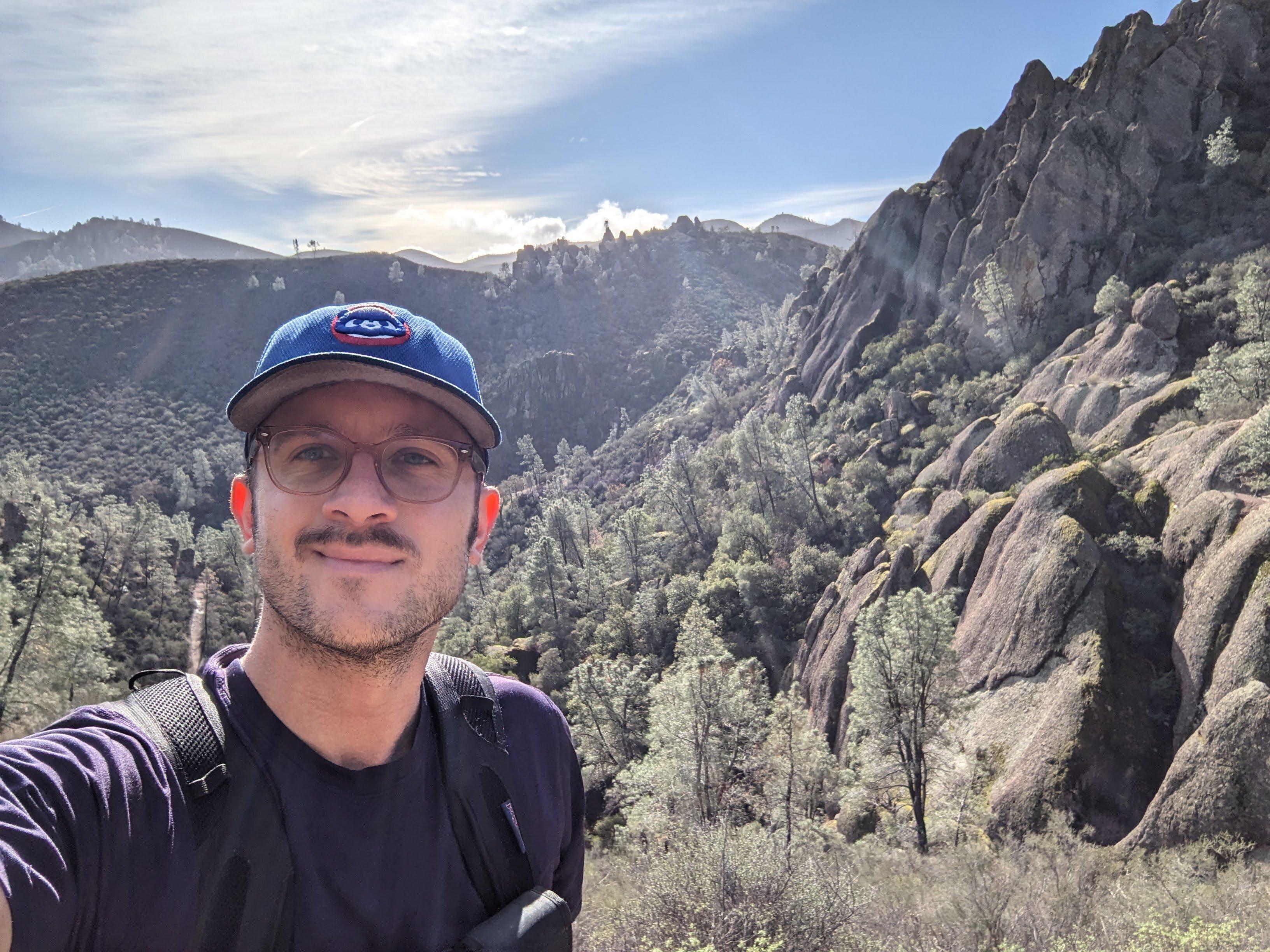 Hiker taking a selfie with dramatic rock formations and mountain landscape at Pinnacles National Park